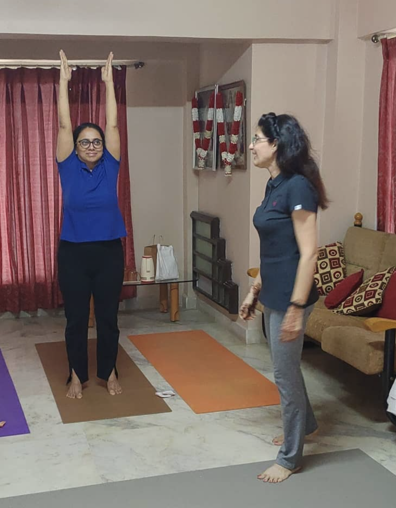 Guiding a student through surya namaskar at a home class